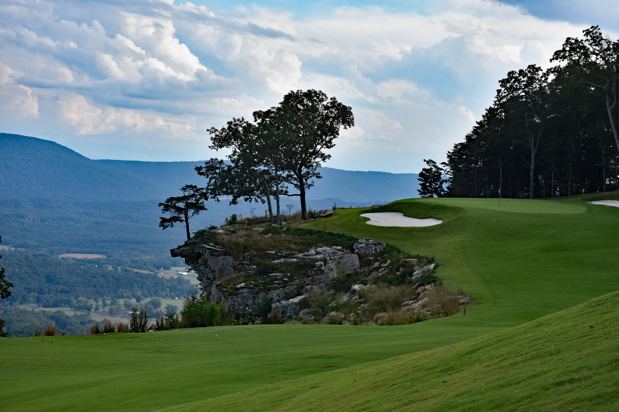 The 18th green at McLemore on a rocky cliff edge above a mountain valley.